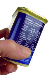 Mano che tiene lattina. Etichetta con informazioni nutrizionali, calorie, grassi, proteine, carboidrati e sodio.