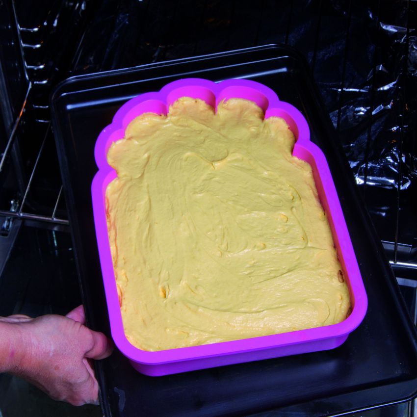 Torta in forno: impasto giallo in stampo viola su teglia nera. Dolce fatto in casa.