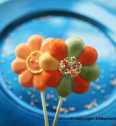 Lecca-lecca a forma di fiore colorati su piatto blu. Dolci decorati con confettini.