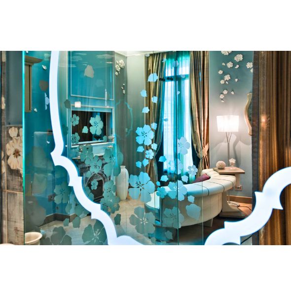 Interni di Chateau Monfort: specchio decorato con fiori, divano e lampada. Design elegante e raffinato.