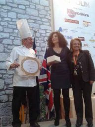 Chef premiato con donne. Riconoscimento culinario, evento gastronomico. Bandiera britannica sullo sfondo.