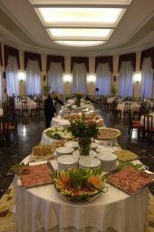 Buffet elegante per evento. Tavoli imbanditi con piatti, fiori e specialità gastronomiche. Catering di lusso.
