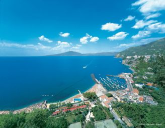 Panorama mozzafiato Le Axidie: mare cristallino, Vesuvio sullo sfondo, costa frastagliata e porticciolo turistico.
