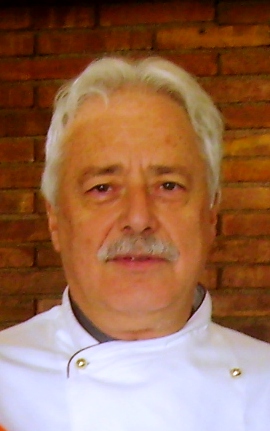 Ritratto di Pino Scaringella, chef italiano con divisa bianca e baffi. Cucina italiana.