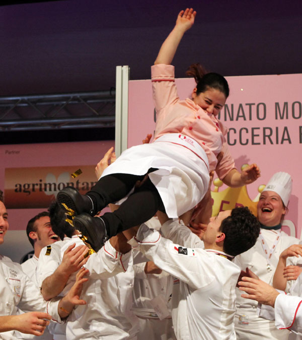 Chef celebrata in aria dai colleghi. Squadra di cucina festeggia il successo. Ristorazione, evento culinario.