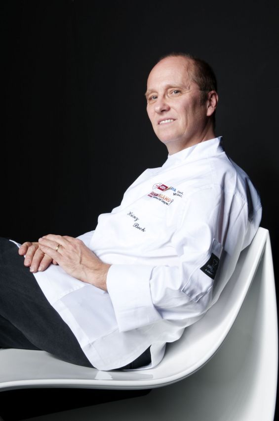 Chef Heinz Beck rilassato su sedia bianca. Cucina gourmet, alta cucina.