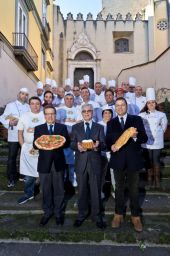 Gruppo di chef e personalità con pizza, babà e pane. Cucina napoletana, tradizione culinaria.