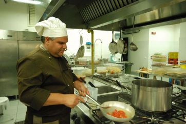 Chef cucina pomodori in padella. Cucina professionale, ristorante, hotel Mahara.