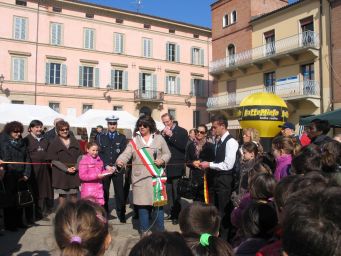 Sindaco taglia nastro a evento cioccolato. Piazza affollata, bandiera italiana. Inaugurazione, festa, folla, autorità.