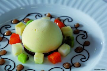 Dolce gourmet: sfera di gelato, frutta fresca a cubetti e decorazioni al cioccolato.