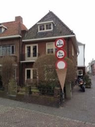 Segnali stradali insoliti a forma di cono gelato davanti a una casa di mattoni in città. Traffico e architettura urbana.