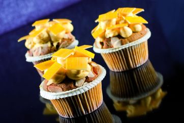 Tre muffin decorati con crema, mandorle e scaglie di formaggio. Dolci da forno gustosi e invitanti.