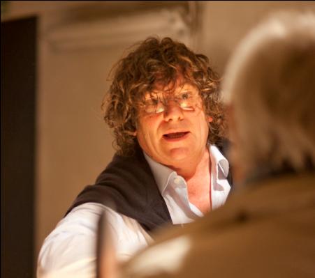 Chef con capelli ricci, camicia bianca e maglione scuro. Cucina gourmet, esperienza culinaria.