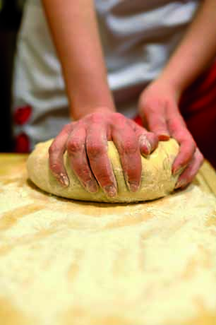 Impasto fatto in casa. Mani che lavorano la pasta su un tavolo di legno infarinato. Ricetta tradizionale.