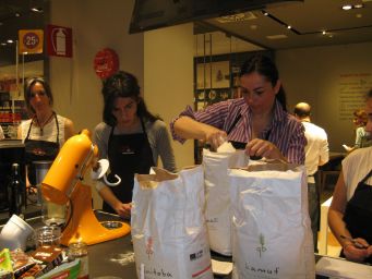 Corso di cucina a Vinitaly: donne preparano impasto con farine speciali. Sacchi di farina Manitoba e Kamut.