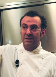 Chef Massimo Bottura con divisa bianca e occhiali. Cucina italiana d'eccellenza.