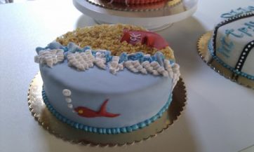 Torta decorata a tema mare: spiaggia, onde e pesciolino rosso. Dolce per feste e compleanni.