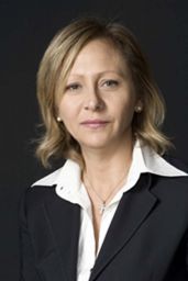 Ritratto formale di donna bionda in giacca. Professionista sorridente con collana.