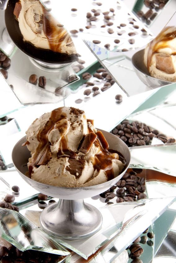 Gelato al caffè in coppa con caramello e chicchi di caffè su specchi. Dessert goloso e invitante.