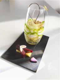 Dolce in vetro con decorazioni e assaggi su ardesia. Dessert gourmet, cucina creativa.