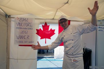 Chef canadese vincitore premio giuria tecnica 2012, sorridente con bandiera Canada. Campionato culinario, cucina professionale.