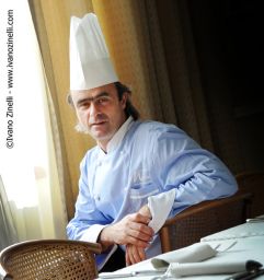 Chef Morini seduto al tavolo. Ristorante di lusso, alta cucina italiana. Cappello da cuoco.