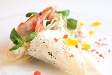 Cono di parmigiano con carciofi, gamberi e bottarga. Piatto gourmet, cucina italiana.