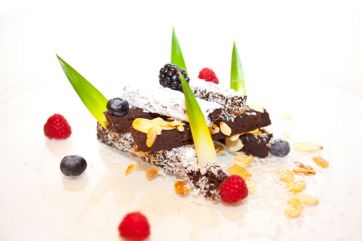 Dolce caprese gourmet con frutti di bosco e mandorle. Dessert al cioccolato, pasticceria creativa.