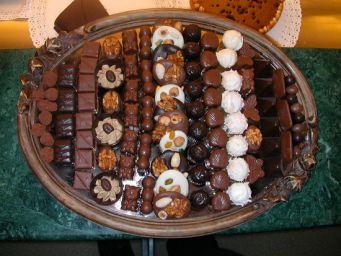 Assortimento di cioccolatini artigianali su vassoio. Cioccolato fondente, al latte e bianco con frutta secca.