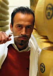 Uomo con coltello e forme di Parmigiano Reggiano. Degustazione formaggio DOP.