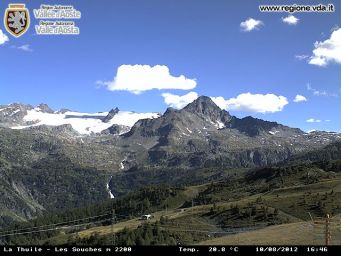Paesaggio montano a La Thuile, Valle d'Aosta. Vette innevate, cielo azzurro con nuvole. Natura alpina e panorama mozzafiato.