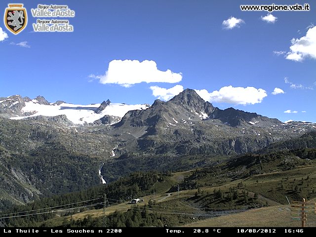 Paesaggio montano a La Thuile, Valle d'Aosta. Vette innevate, cielo azzurro con nuvole. Natura alpina e panorama mozzafiato.