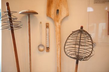 Utensili tradizionali per Parmigiano Reggiano: mestolo, termometro, pala in legno e attrezzi caseari.