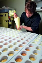 Pasticcere decora dolcetti. Sac à poche con crema. Stampo per dolci, preparazione artigianale.