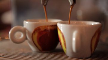 Preparazione espresso italiano. Tazzine di caffè riempite da macchina professionale. Aroma intenso.