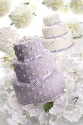 Torta nuziale a tre piani lilla con pois bianchi e fiori bianchi. Dolci per matrimonio.