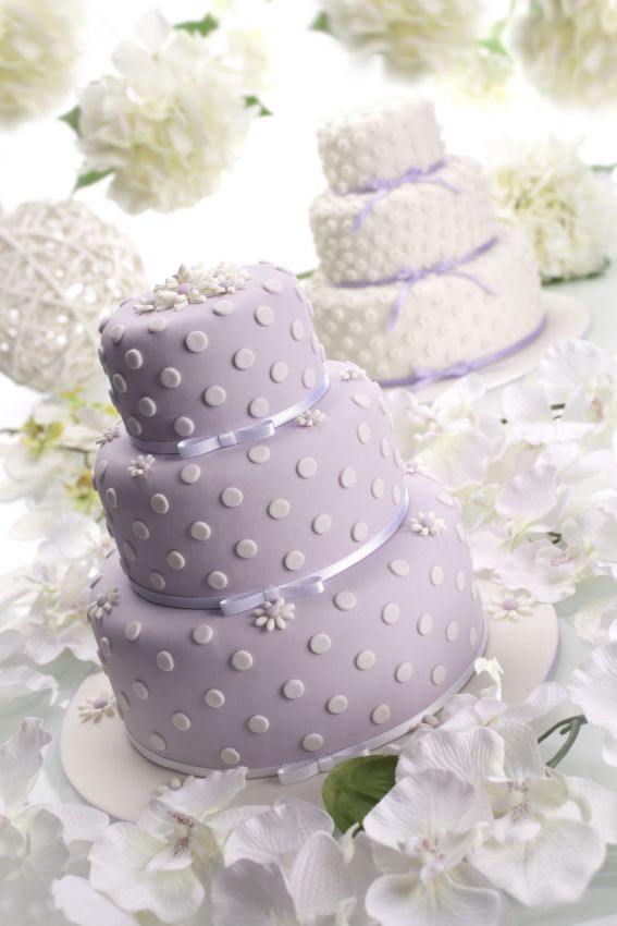Torta nuziale a tre piani lilla con pois bianchi e fiori bianchi. Dolci per matrimonio.