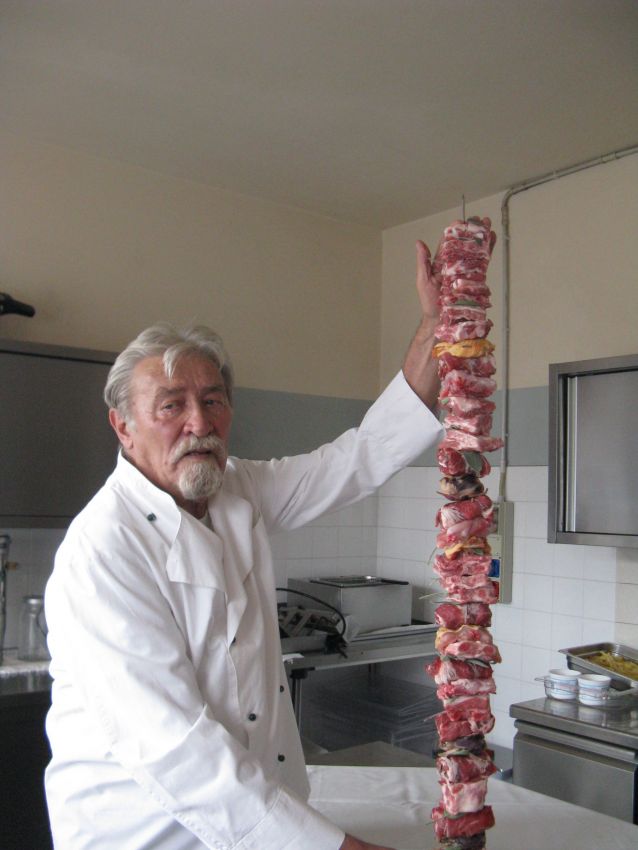 Chef con spiedino gigante di carne. Cucina tradizionale italiana, ricetta regionale. Specialità gastronomica.