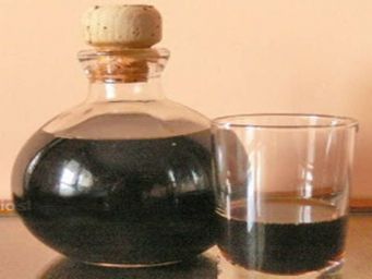 Bottiglia e bicchiere di nocino, liquore tradizionale italiano alle noci.