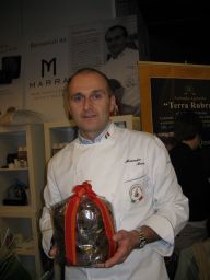 Chef italiano con panettone artigianale, confezione regalo con nastro rosso. Pasticceria Marra, eccellenza culinaria.