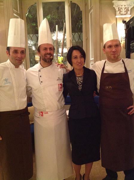 Tre chef in divisa con una donna in giacca. Ristorante, cucina italiana.