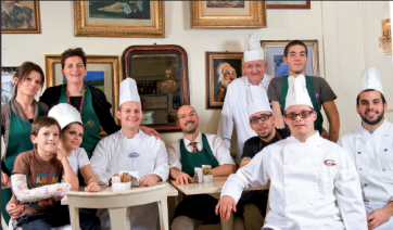 Gruppo di chef e personale di ristorante italiano sorridenti, cucina tradizionale.