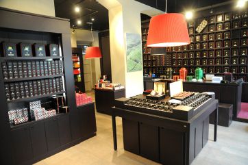 Interno negozio di tè. Scaffali di tè neri, lampade rosse, design elegante. Vendita tè pregiati.