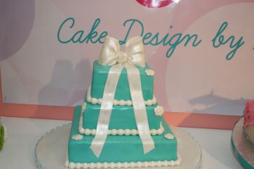 Torta a piani turchese con fiocco bianco. Cake design per eventi e feste italiane.