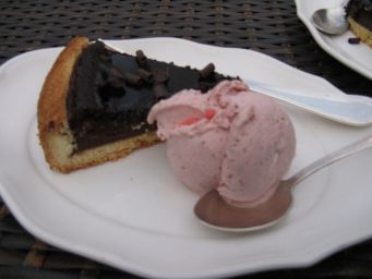 Fetta di torta al cioccolato con gelato alla fragola su piatto bianco. Dessert goloso.