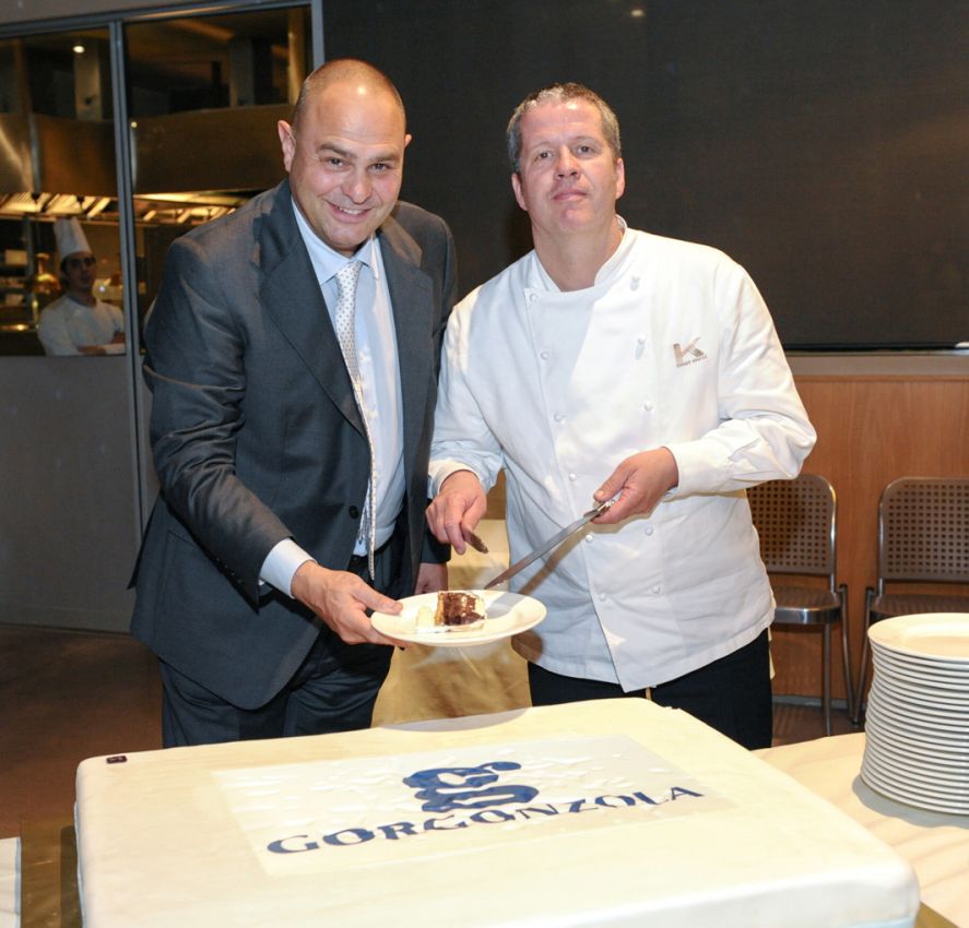 Renato Invernizzi e Ernst Knam tagliano torta Gorgonzola. Chef, evento gastronomico, formaggio italiano.