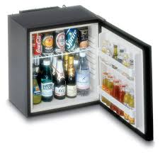Mini frigo bar aperto con bevande: lattine, bottiglie d'acqua e succhi di frutta. Frigorifero compatto.