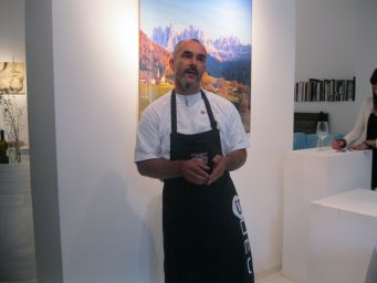 Chef in grembiule nero. Degustazione vini, evento culinario. Montagne sullo sfondo.
