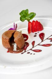 Tortino al cioccolato con cuore fondente, fragole fresche e decorazioni. Dessert delizioso.