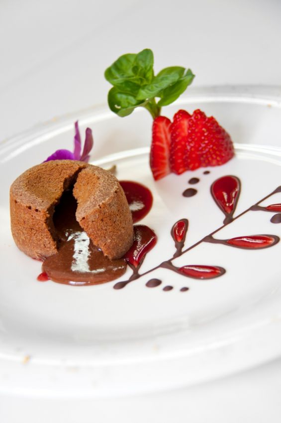 Tortino al cioccolato con cuore fondente, fragole fresche e decorazioni. Dessert delizioso.